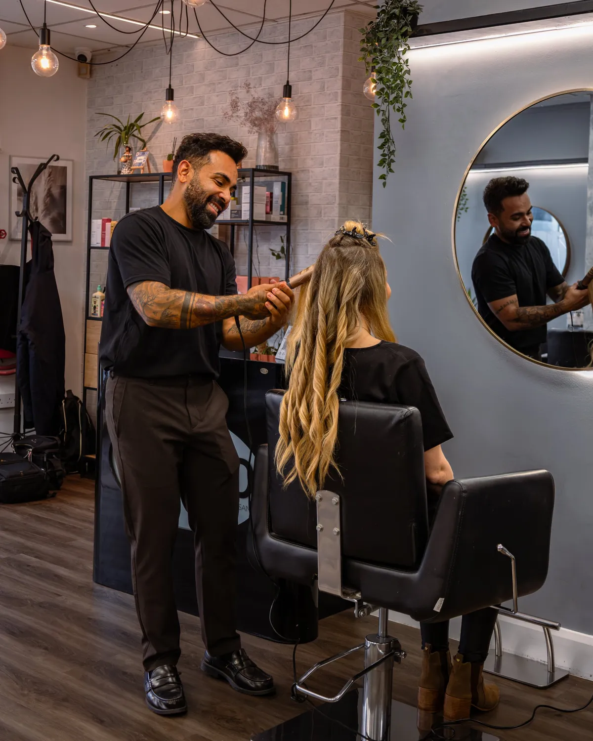 Stylist using a heated styling tool on long blonde hair.