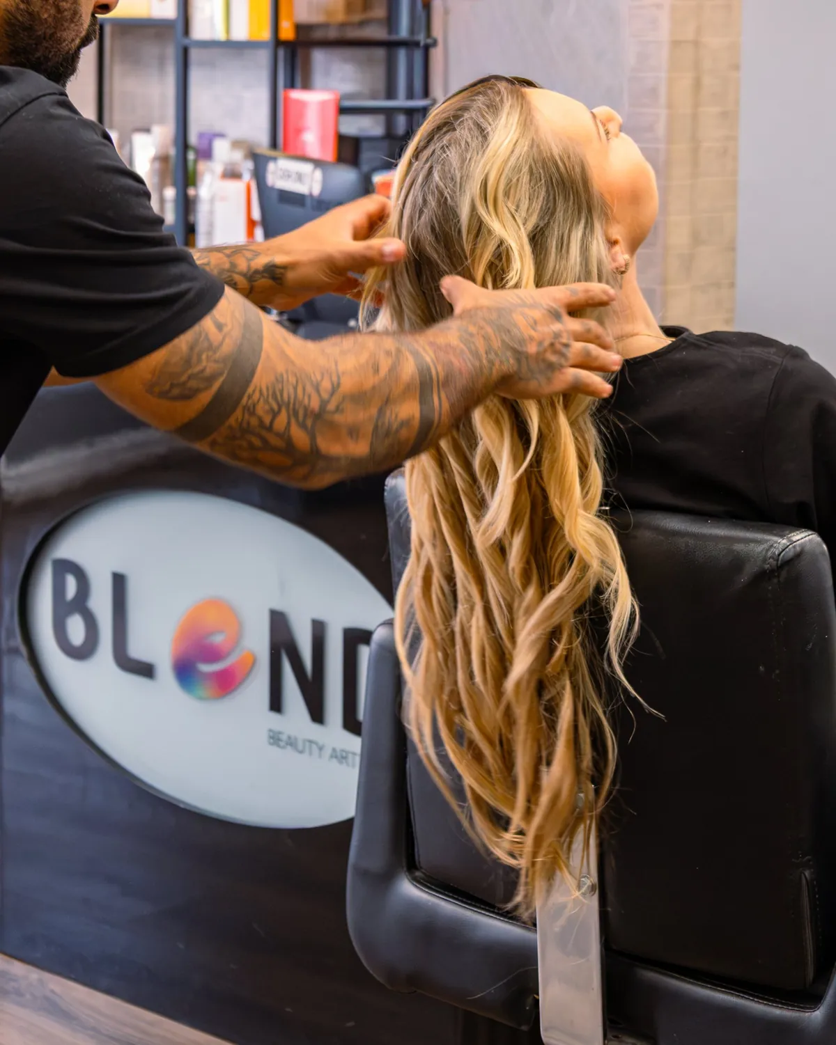 Stylist arranging a client's long blonde waves.