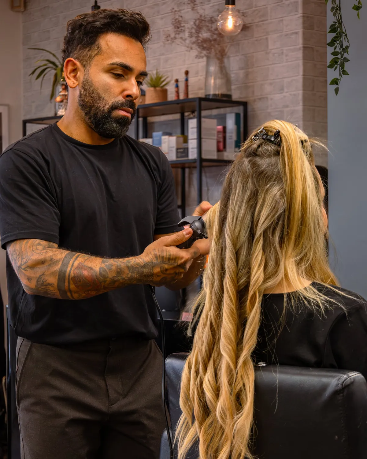 Stylist creating waves in a client's long blonde hair.