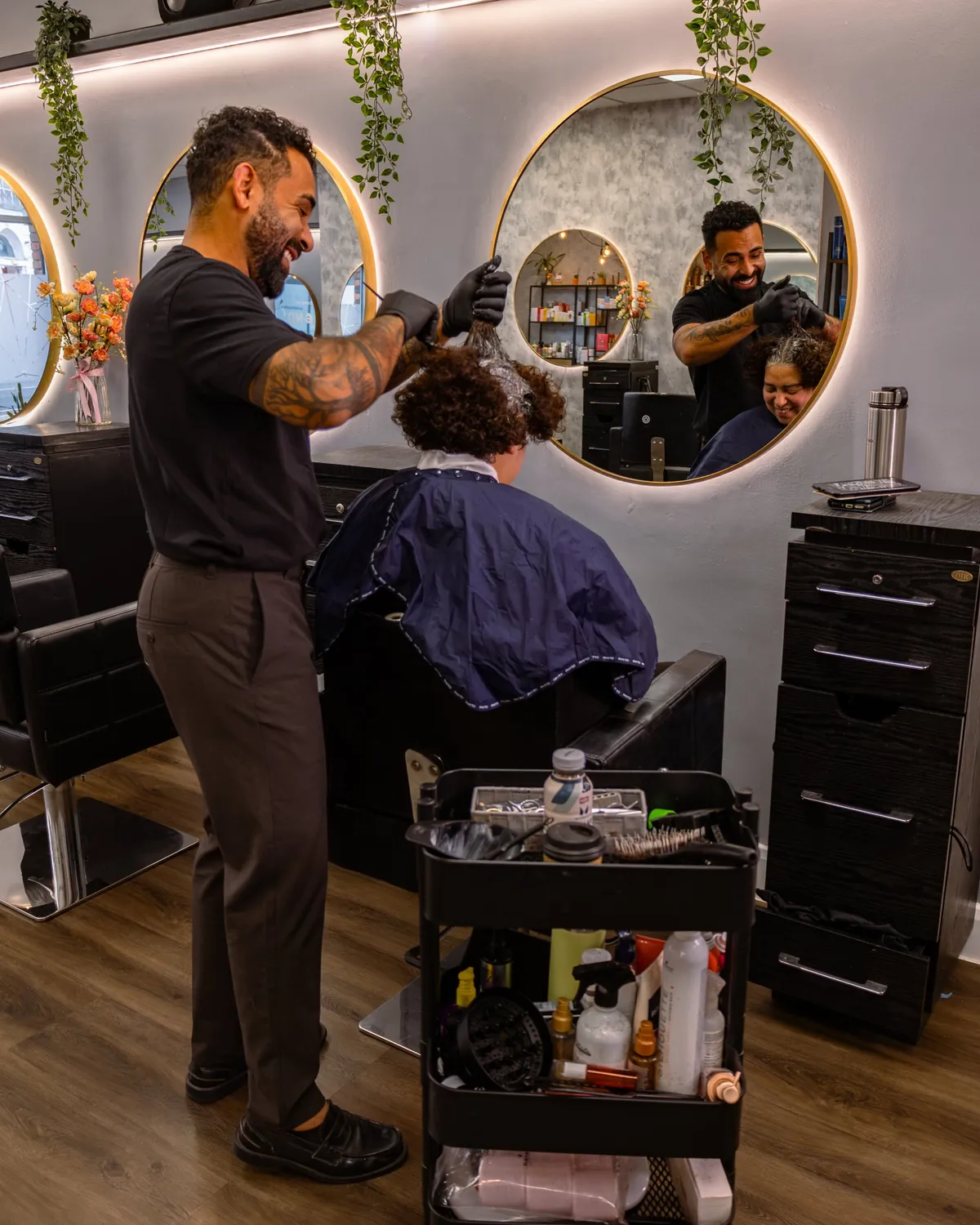 Colourist applying hair colour to a client's curly hair.