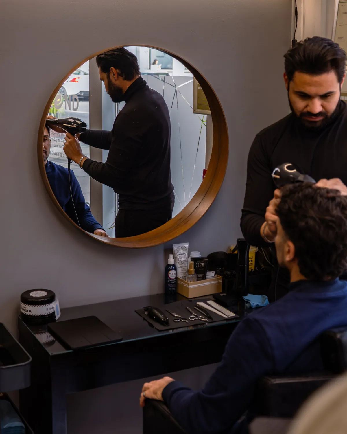 Stylist blow-drying a male client's hair.