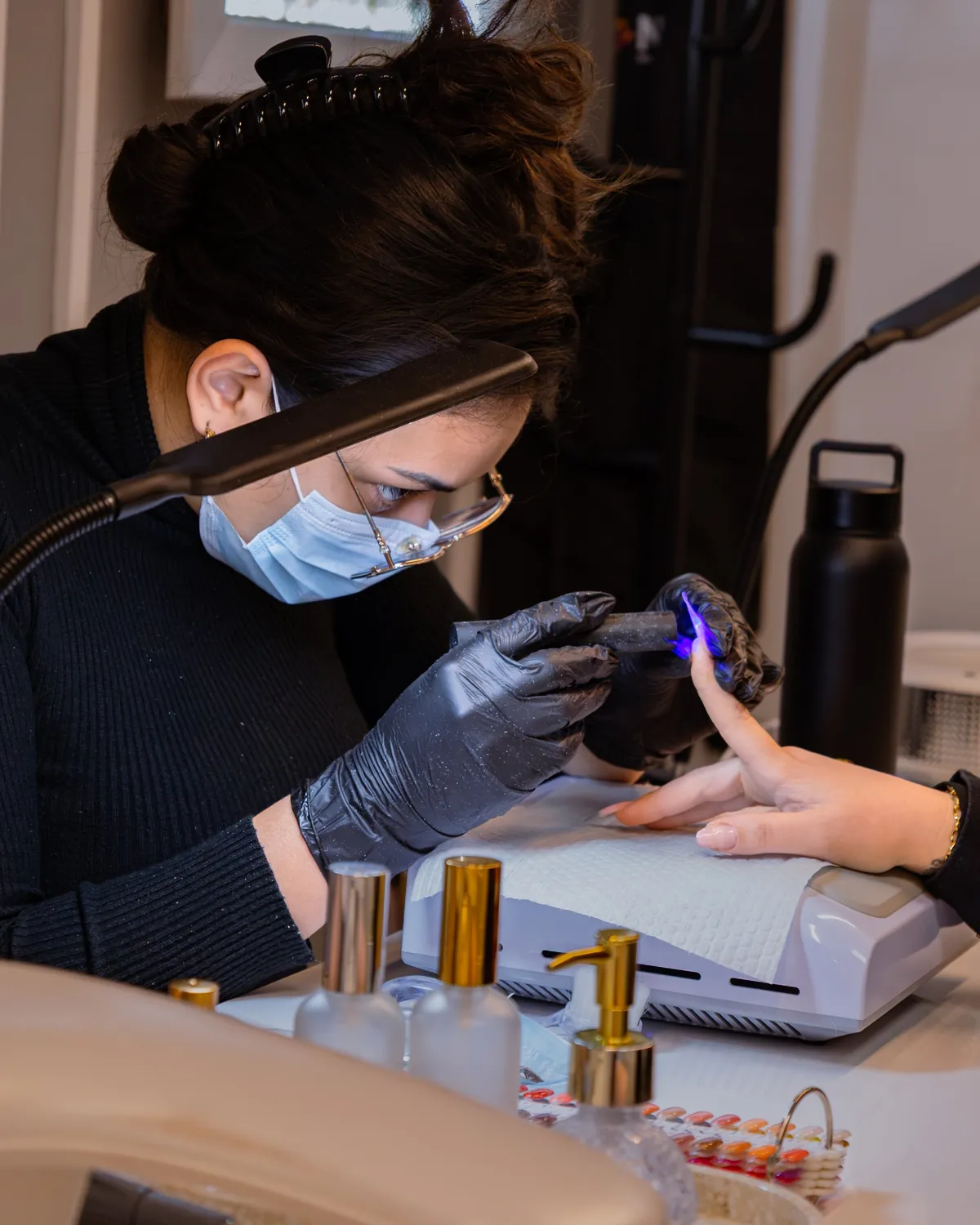 Nail technician using a curing light during a nail treatment.
