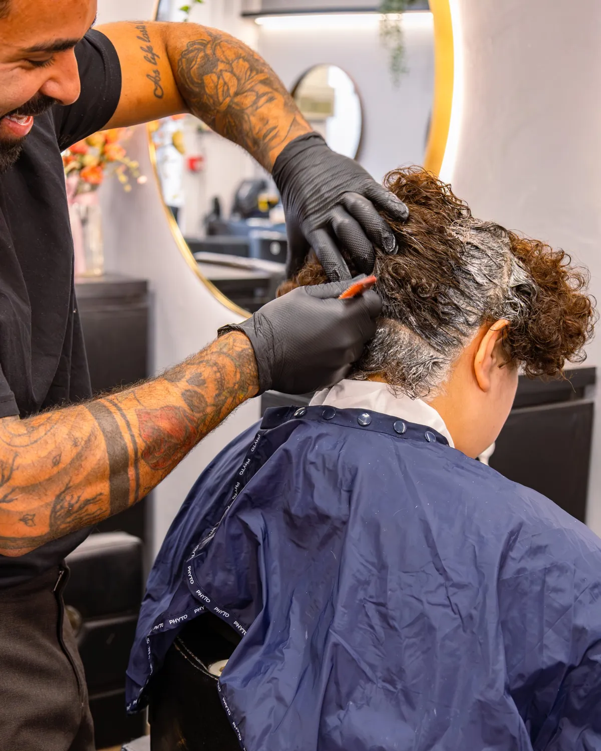 Close-up of colour being applied to curly hair with a brush.